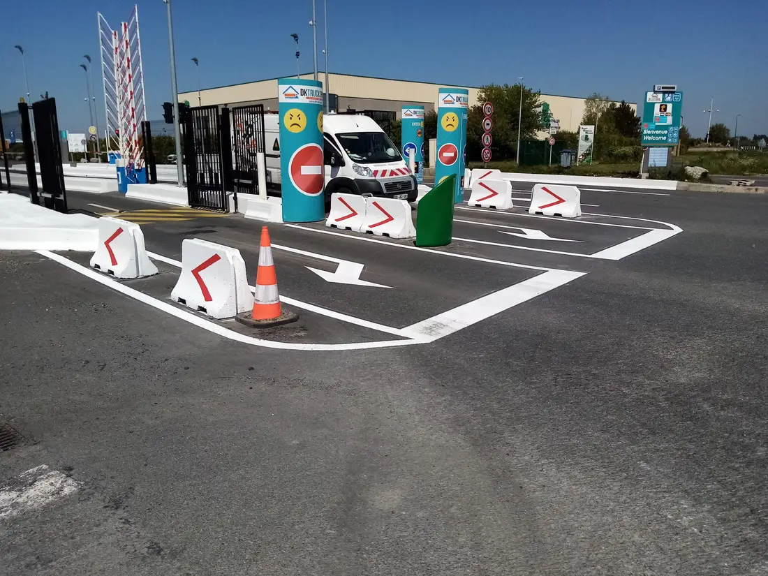 Marquage blanc et séparateurs de voie à l'entrée d'un site, avec panneau de sens interdit