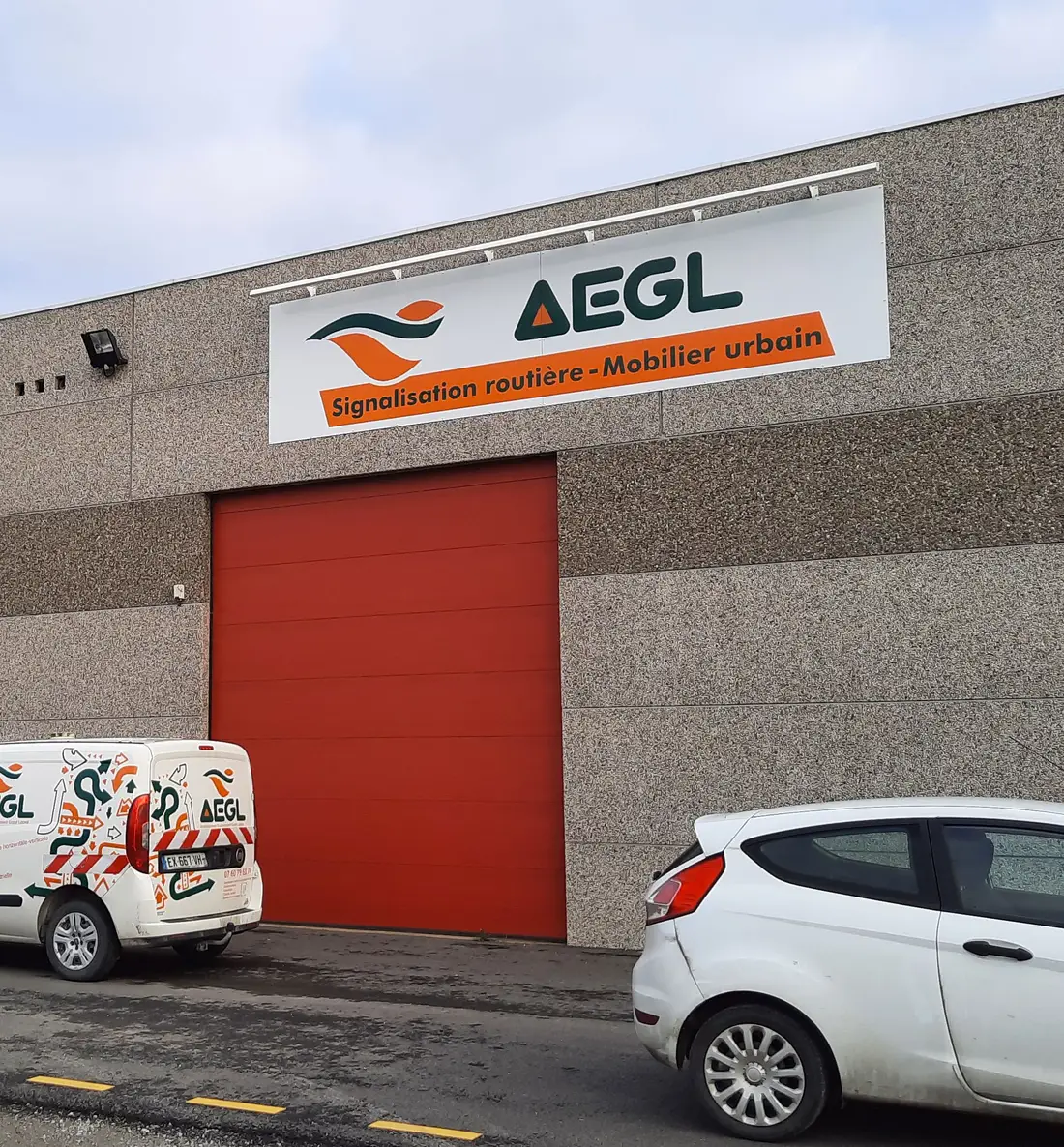 Façade du bâtiment AEGL et véhicules de service stationnés devant le quai