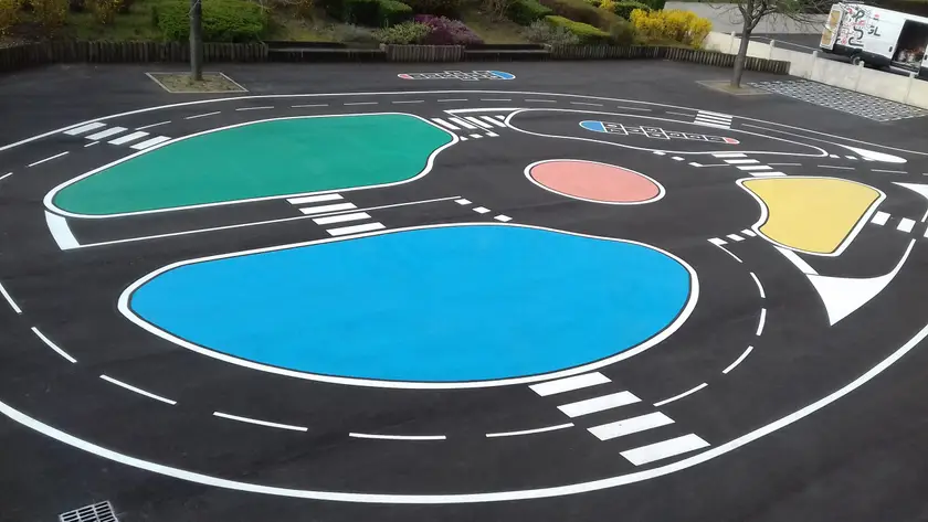 Circuit routier miniature et aplats de couleur peints sur une aire goudronnée