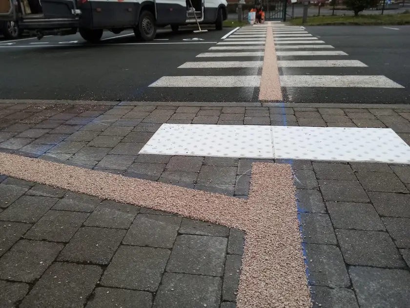 Passage piétons, bande d'éveil de vigilance blanche et bande beige gravillonnée sur un trottoir pavé
