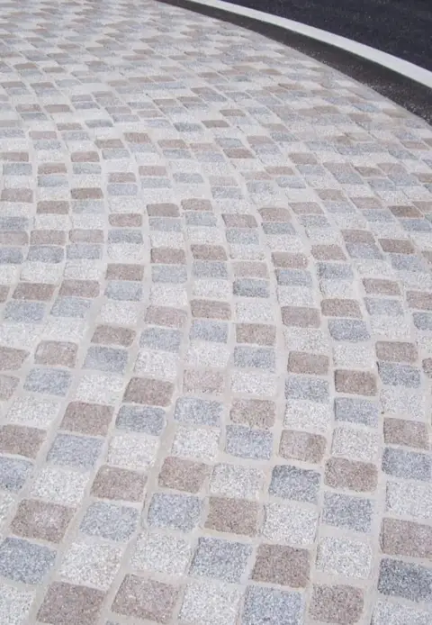 Pavage décoratif gris et rosé en bordure d'une chaussée