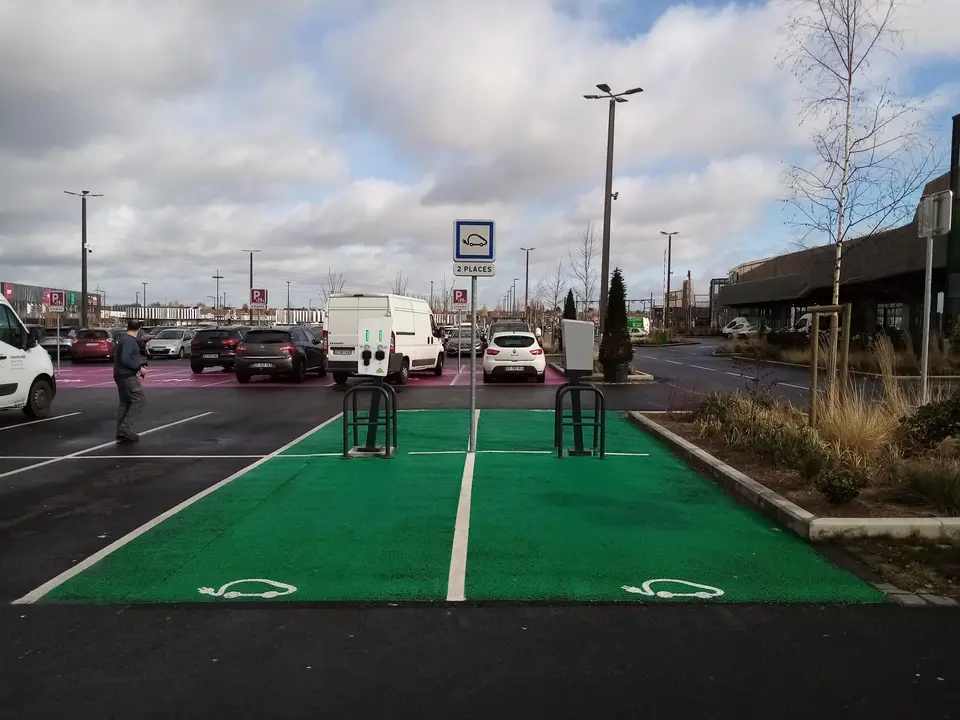 Deux places de stationnement vertes à pictogramme de véhicule électrique, avec bornes de recharge