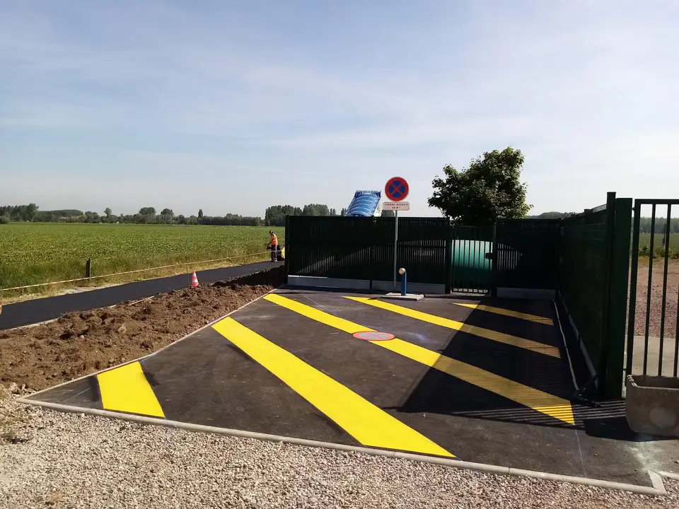 Zébra jaune peint sur un accès goudronné devant un portail